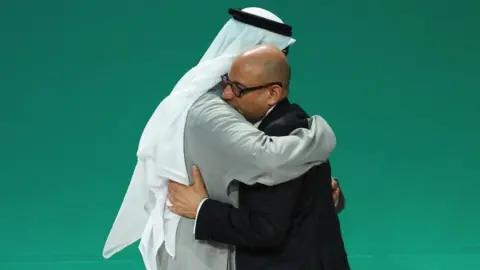 Reuters COP28 President Sultan al-Jaber and UNFCCC Executive Secretary Simon Stiell hug.