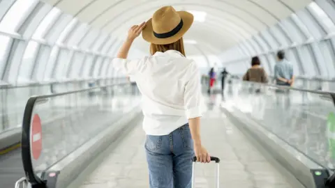 Getty Images Female traveller with suitcase at airport