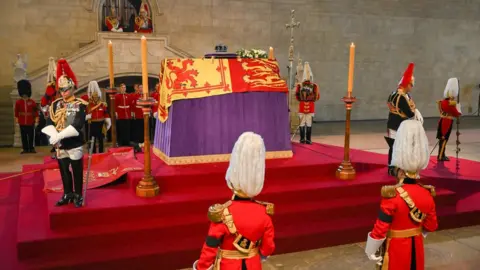 PA Media The coffin of Queen Elizabeth II, draped in the Royal Standard with the Imperial State Crown placed on top, lays on the catafalque in Westminster Hall