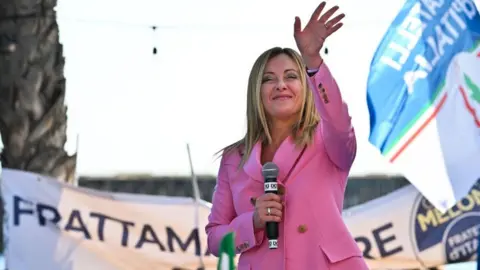 ANDREAS SOLARO/AFP Giorgia Meloni waves as she delivers a speech on September 23, 2022 at the Arenile di Bagnoli beachfront location in Naples