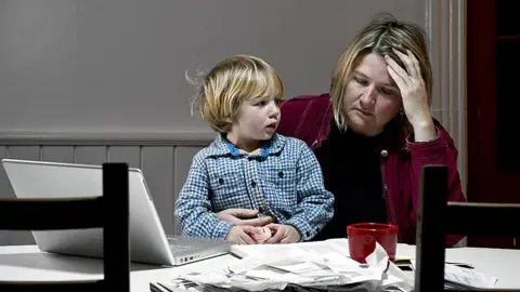 Getty Images Single mum with toddler goes through a pile of bills