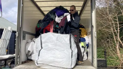 Katherine Ganczakowski/BBC Clothes being moved into large tonne bags in a white van, ready to be donated
