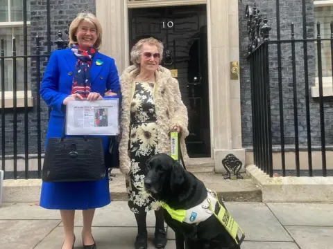 Justin Dealey/BBC Jill Allen-King with Jagger and Southend MP Anna Firth outside No 10 Downing Street