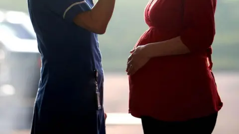 PA Media NHS staff member and pregnant woman