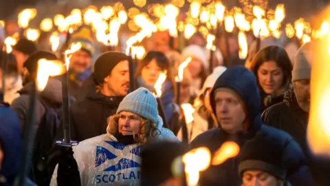 PA Media The torchlight procession in Edinburgh has returned after a four-year absence with thousands lining the streets for the spectacular light show