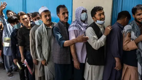 Getty Images Afghans wait in long lines for hours at the passport office in Kabul