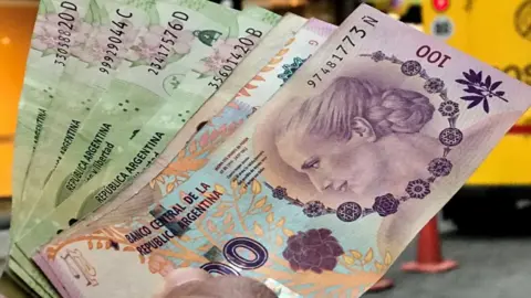 Reuters A man shows Argentine pesos outside a bank in Buenos Aires' financial district