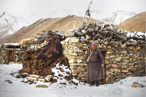 Andrew Newey A herder stands in front of his stone house