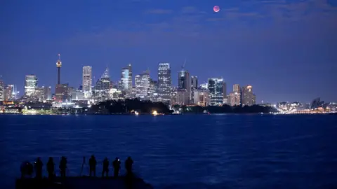 Getty Images The moon is seen turning red over the Sydney skyline during a total lunar eclipse on July 28, 2018 in Sydney, Australia.