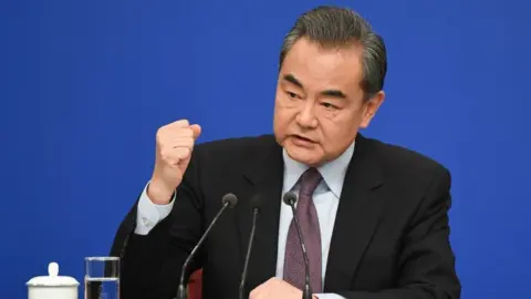 Getty Images China's Foreign Minister Wang Yi reacts as he answers a question during a National People's Congress press conference in Beijing on March 8, 2019.