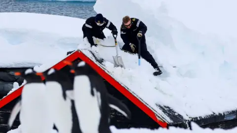 PA Media Royal Navy personnel from HMS Protector digging out the Port Lockroy site