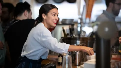 Getty Images Rep. Alexandria Ocasio-Cortez works behind the bar at the Queensboro Restaurant