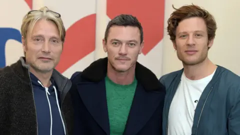 David M. Benett/Getty Images Luke Evans pictured with fellow actors Mads Mikkelsen (left) and James Norton