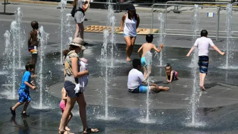 AFP/Getty Images A group of people pictured trying to stay cool in a fountain