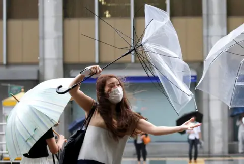 Toru Hanai / Reuters A woman using an umbrella struggles against heavy rain and wind