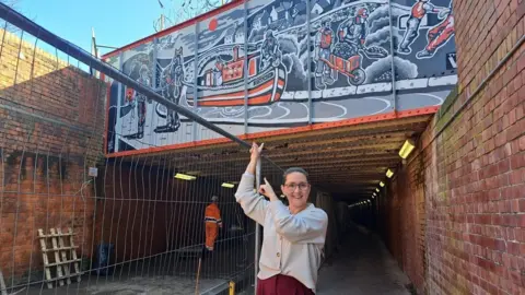 Swindon Borough Council Marina Strinkovsky pointing to the mural in Swindon