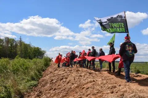 BBC Demonstrators forming a red line on the edge of the forest