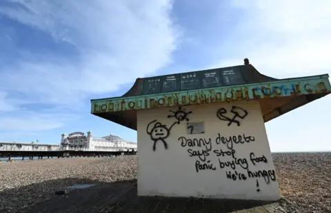 Getty Images Graffiti on Brighton beach urging people to stop panic buying