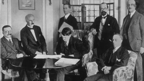 Topical Press Agency/Getty Images Michael Collins signing the Anglo-Irish Treaty on 6 December 1921