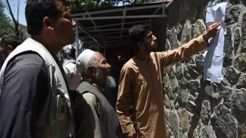 AFP Men check a list of casualties after a car bombing in Kabul, 1 July