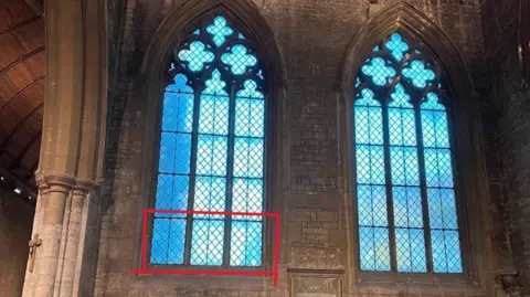 Geoff Stead Two large glass windows inside the church, the window on the left has three panels at the bottom of the window highlighted in red, this shows where the stained glass will be reinstalled. 