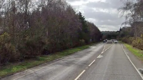 Google Open rural road with cars in the distance. There are hedges alongside the road