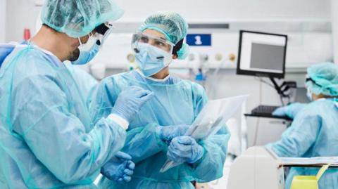 Surgical staff wearing PPE in conversation 
