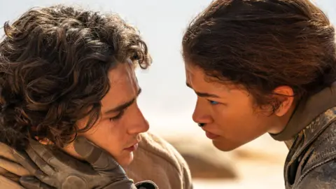 Warner Bros Still from Dune: Part Two featuring Timothée Chalamet and Zendaya.