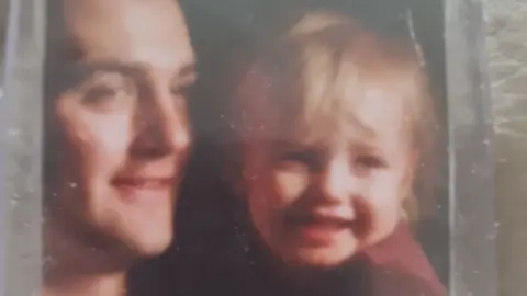 Juliette Murphy Man holds smiling child on grainy quality image.