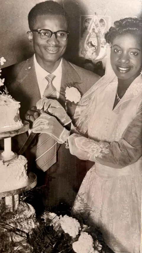 Steve Reeves A black and white photograph of a couple on their wedding day, cutting the cake