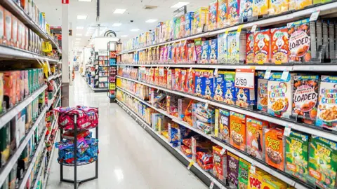 A grocery aisle with boxes of cereal lining the shelves.