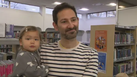 A father holding his toddler daughter in a library