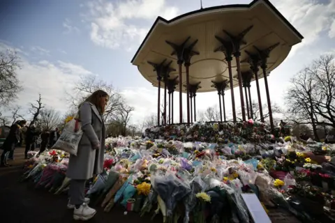 Getty Images A well-wisher pauses at the tributes to honour Sarah Everard at the bandstand on Clapham Common in south London on March 15, 2021. 