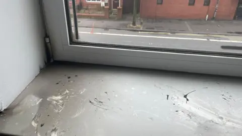 Tejal Samat and Nishath Mohammed An windowsill covered with smoke damage.