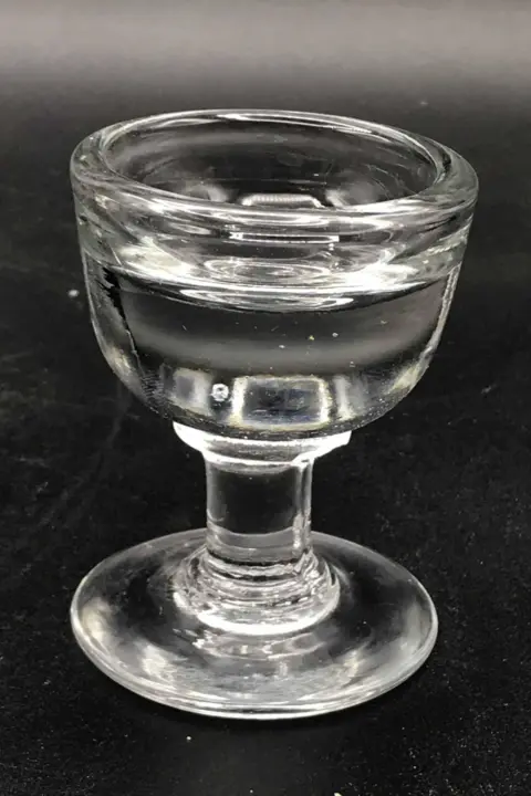 A small thick glass used for a penny lick of ice cream. Has a short stem with a base and a cup that holds very little