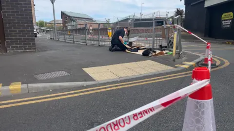 A police worker behind a cordon. The tape reads "inner cordon"