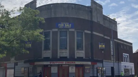 LDRS A curved red brick building with signs saying Stafford Cinema and For Sale