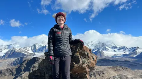 Aoife McKenna Aoife McKenna wearing a winter hat and glasses with snowy hills behind her