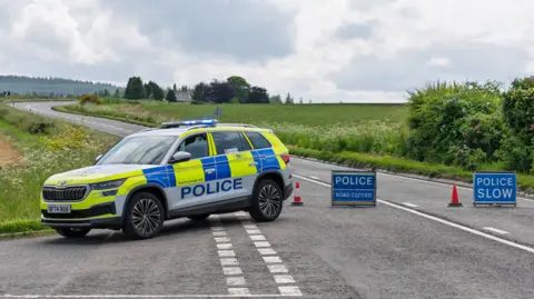 Police car next to 'police accident' signs on a rural road.