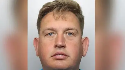 PA Mug shot of Jake Turton, clean shaven and with short blonde hair pulled back. He looks straight into the camera, expressionless.