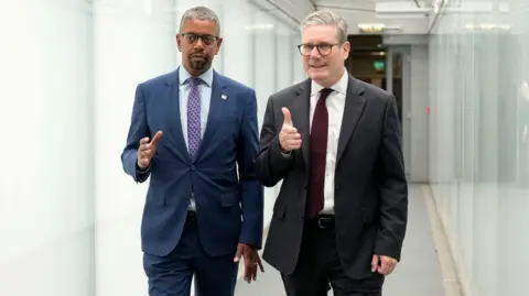 PA Media Vaughan Gething stood next to Sir Keir Starmer in a corridor between Ty Hywel, the Welsh Parliament's office building, and the main Senedd building housing the debating chamber.