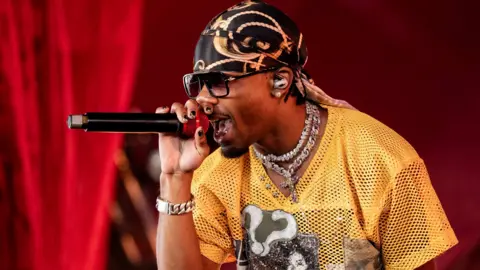 Getty Images D4vd at Coachella last year, wearing a yellow mesh T-shirt and singing into a microphone