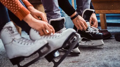 A couple putting on ice skates.