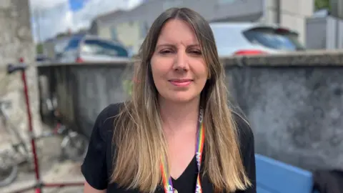 Woman with long brunette hair wearing an NHS lanyard