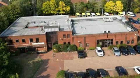 Steve Hubbard/BBC A drone aerial image of the Bedford Emergency Operations Centre on Hammond Road. The red-brick building is over two storeys and there are several cars outside in a car park.