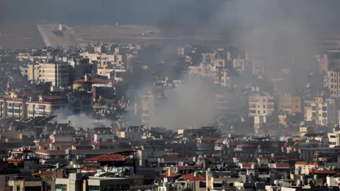 Reuters A plane takes off from a runway in the background as smoke rises from a city in the foreground.