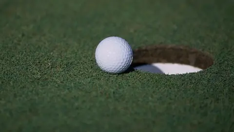 A general view of a golf ball sitting near a hole
