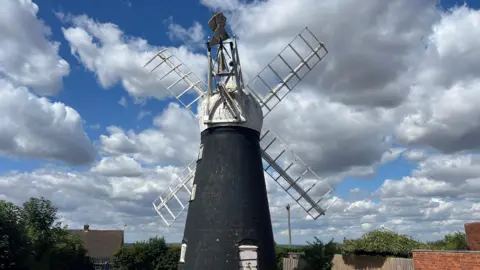 Picture of a four-sailed windmill, showing deterioration of the sails and fan tail