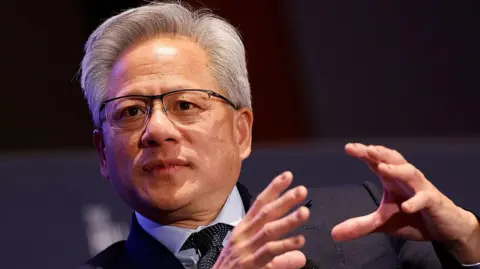 CEO of Nvidia Jensen Huang speaks on AI at the return of American manufacturing at the Hill and Valley Forum at the US Capitol. He is dressed formally in a dark suit and gesturing with his hands 