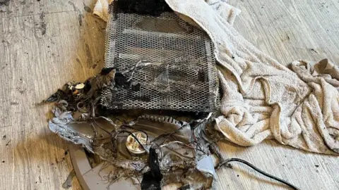 A burnt out heater with a beige towel next to it.